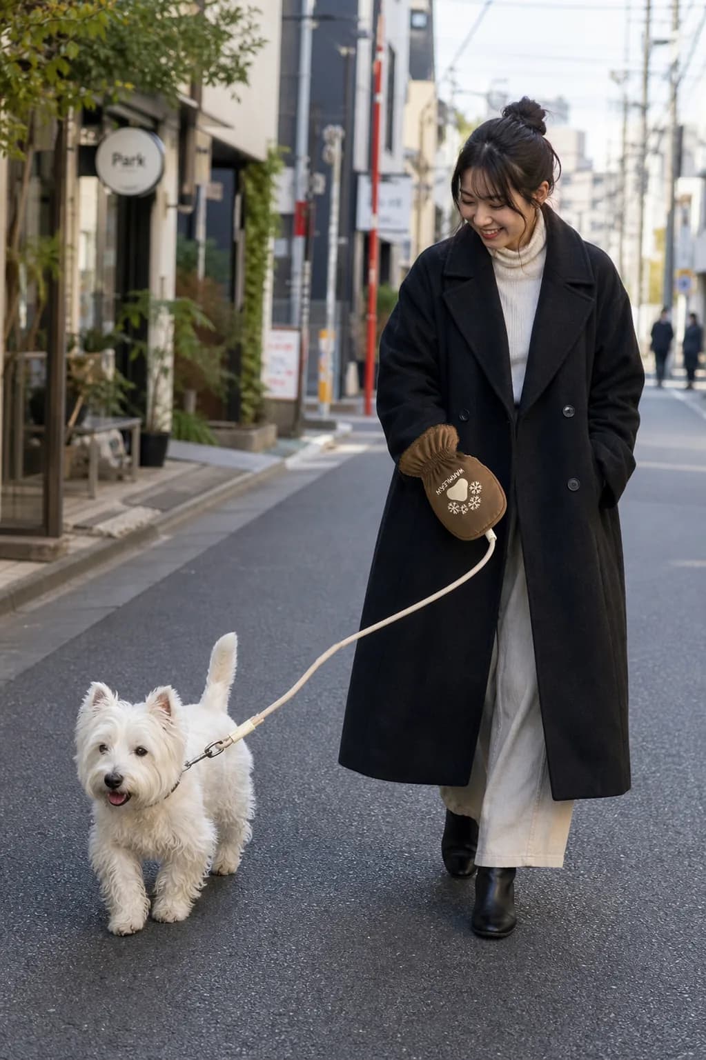 Woman walking a small white dog with WarmLeash on a refined city street.